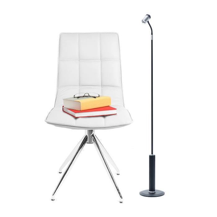 Modern workspace with a white designer chair and a black and silver LightBob™: Cordless, Go Anywhere LED Task Floor Light, providing focused illumination.